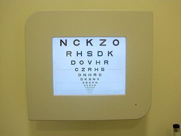 A white wall-mounted display featuring a clear eye chart for vision testing purposes.
