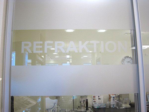 A white door featuring a sign that reads "refraction" indicating a specific entrance or room.