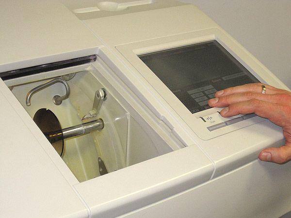 A person operates a cleaning machine to maintain another machine, ensuring optimal performance and cleanliness.